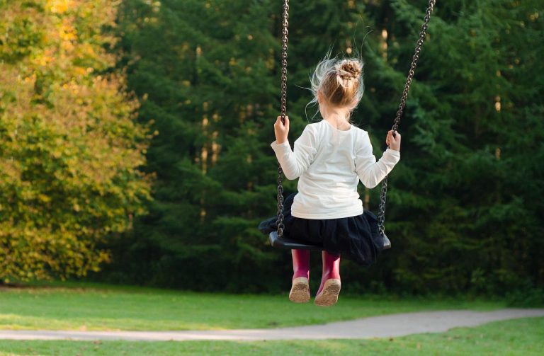 Kleurrijke schommel in een groene tuin met kinderen die genieten van buitenspelen